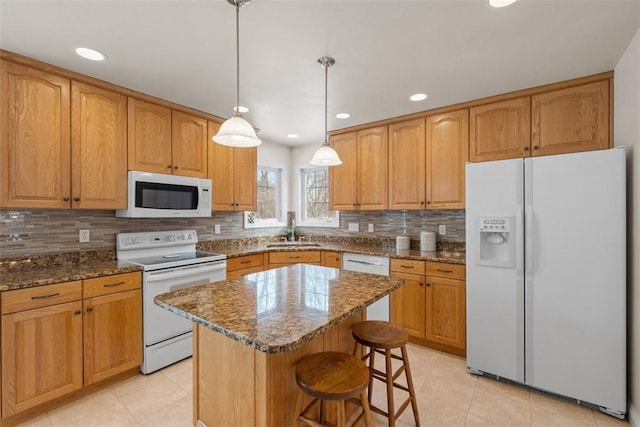 kitchen with stone counters, white appliances, a sink, hanging light fixtures, and a center island