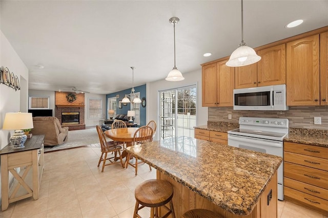 kitchen with stone counters, white appliances, a kitchen island, open floor plan, and tasteful backsplash