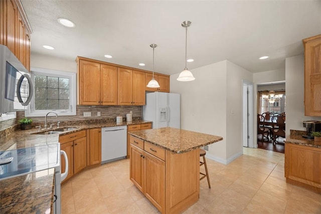 kitchen with a center island, pendant lighting, decorative backsplash, a sink, and white appliances