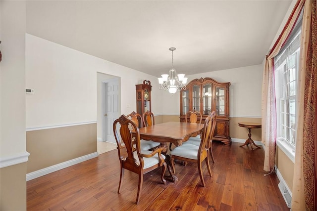 dining room with an inviting chandelier, baseboards, and dark wood finished floors