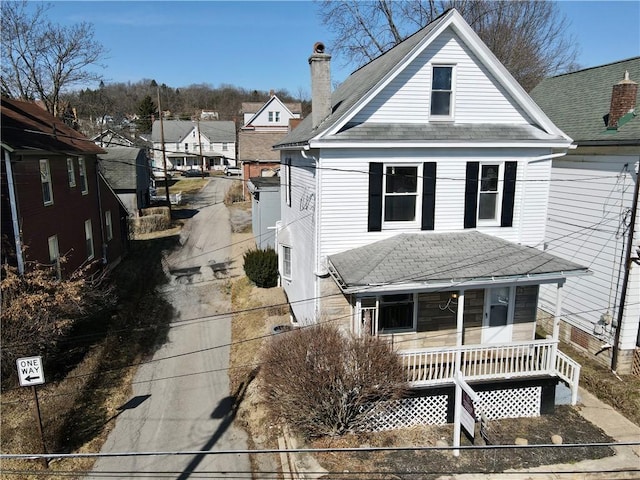 exterior space with covered porch, a chimney, and roof with shingles