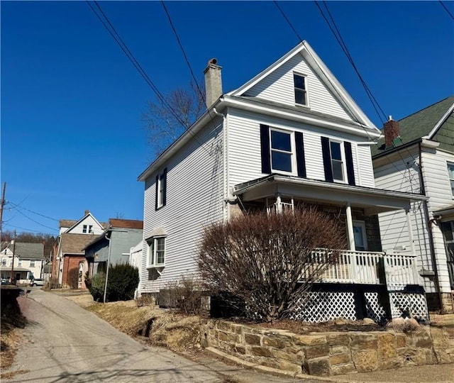 view of front facade with a porch and a chimney