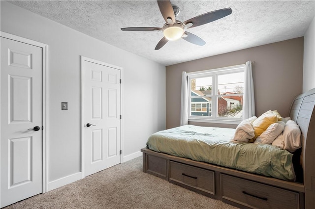 bedroom featuring light carpet, ceiling fan, a textured ceiling, and baseboards