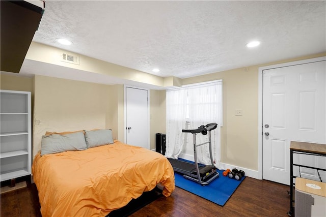 bedroom with baseboards, visible vents, dark wood-type flooring, a textured ceiling, and recessed lighting