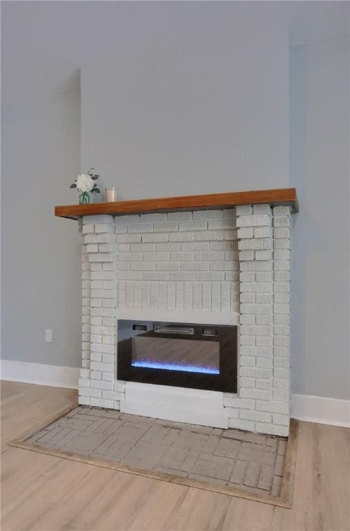 room details with a brick fireplace, baseboards, and wood finished floors