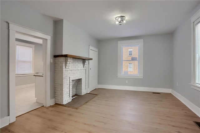 unfurnished living room featuring baseboards, a fireplace, light wood-style flooring, and a healthy amount of sunlight