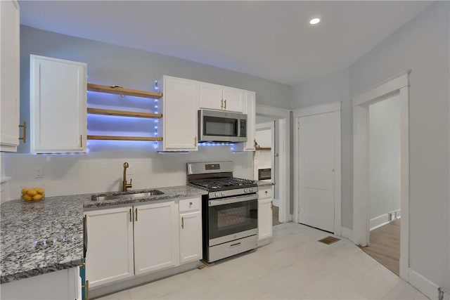 kitchen featuring light stone counters, stainless steel appliances, white cabinetry, open shelves, and a sink