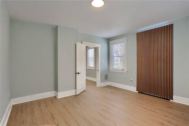 empty room featuring baseboards, visible vents, and light wood finished floors