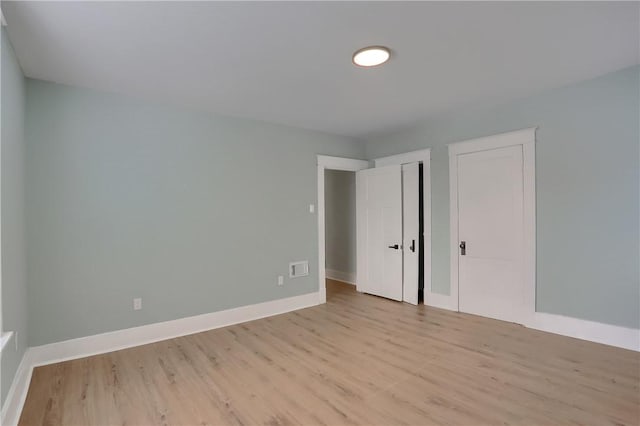 unfurnished bedroom with two closets, light wood-style flooring, and baseboards