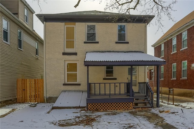 snow covered rear of property featuring brick siding