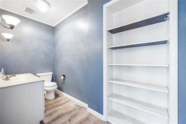 bathroom featuring toilet, vanity, wood finished floors, and visible vents