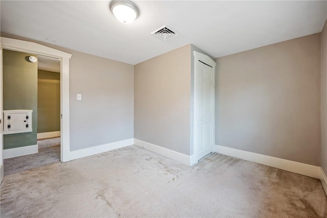 empty room with carpet, visible vents, and baseboards