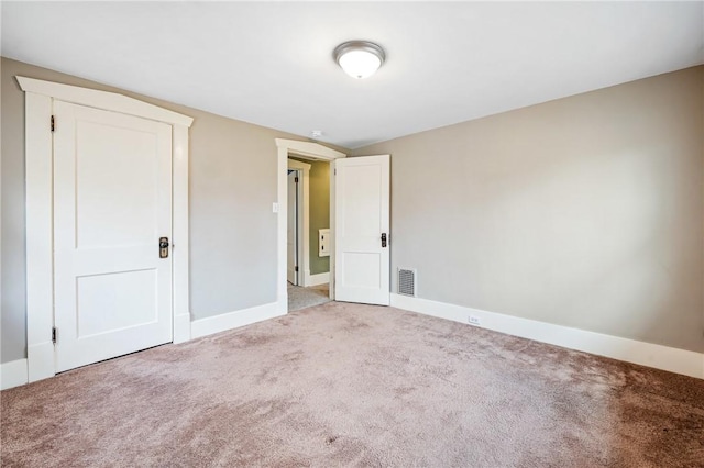 empty room with carpet floors, baseboards, and visible vents