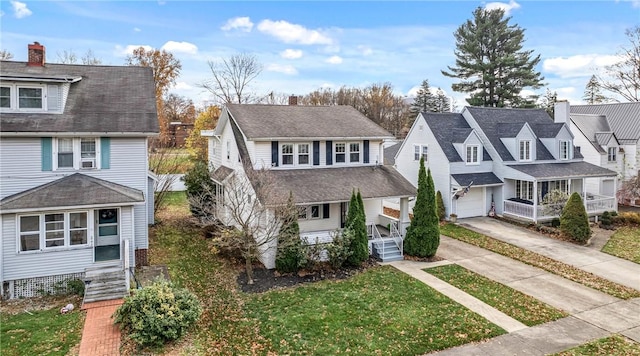 traditional style home with a chimney, concrete driveway, covered porch, a residential view, and a front lawn