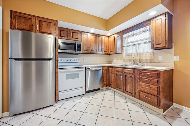 kitchen with light tile patterned flooring, stainless steel appliances, a sink, light countertops, and brown cabinetry