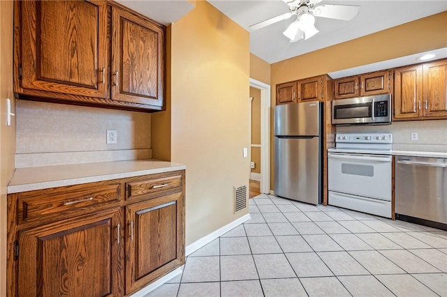 kitchen with brown cabinets, light tile patterned floors, light countertops, visible vents, and appliances with stainless steel finishes