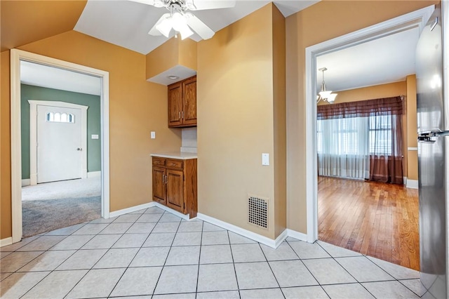 interior space featuring ceiling fan with notable chandelier, light tile patterned floors, visible vents, and baseboards