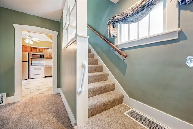 stairway featuring carpet, tile patterned flooring, ceiling fan, and visible vents