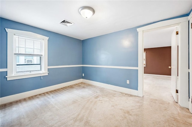 unfurnished room with carpet flooring, visible vents, and baseboards