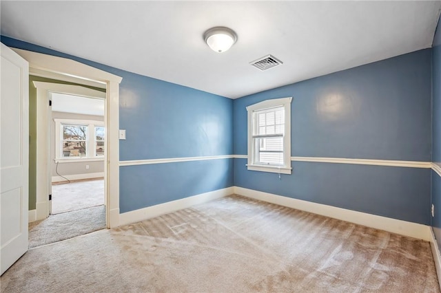 spare room with carpet floors, plenty of natural light, and visible vents