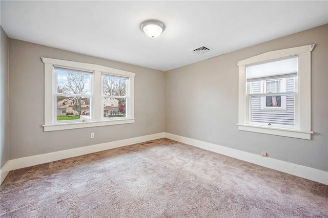 carpeted spare room featuring visible vents and baseboards