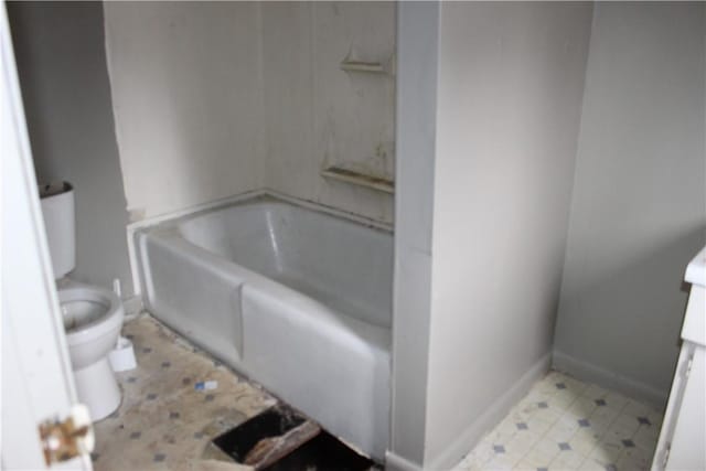 full bath featuring a tub to relax in, baseboards, vanity, and toilet