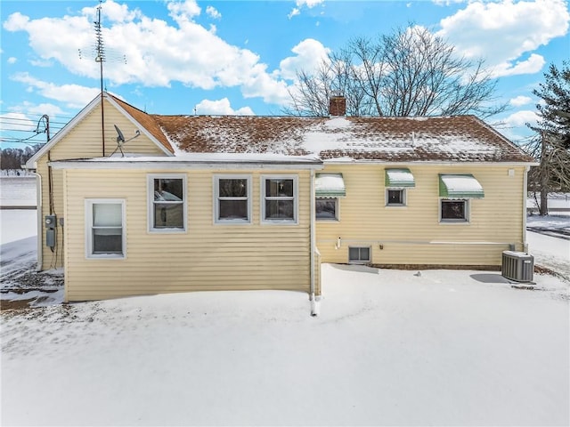 snow covered house with a chimney and central air condition unit