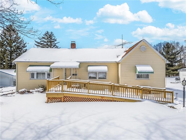 snow covered rear of property featuring a chimney and a deck