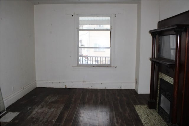 unfurnished living room with dark wood-style flooring and a tiled fireplace