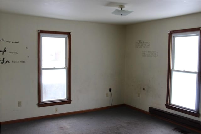 spare room featuring dark colored carpet, baseboards, visible vents, and baseboard heating