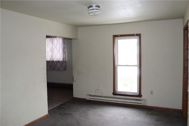 spare room featuring a healthy amount of sunlight, baseboards, baseboard heating, and dark colored carpet