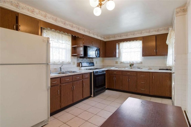 kitchen featuring gas range, freestanding refrigerator, light countertops, black microwave, and a sink