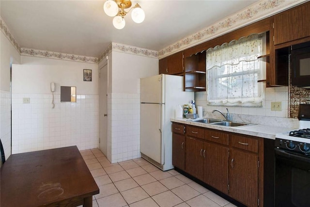 kitchen with light tile patterned floors, light countertops, black appliances, open shelves, and a sink