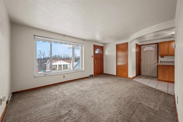 spare room with baseboards, light tile patterned floors, visible vents, and light colored carpet