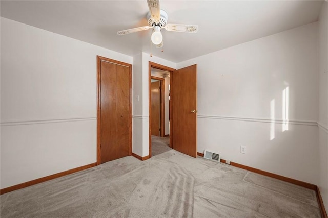 unfurnished bedroom featuring light carpet, baseboards, visible vents, a ceiling fan, and a closet