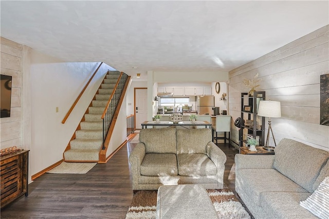 living area featuring stairs, dark wood-style flooring, and baseboards