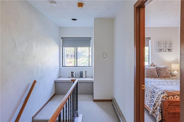 corridor with a baseboard radiator, baseboards, and carpet flooring