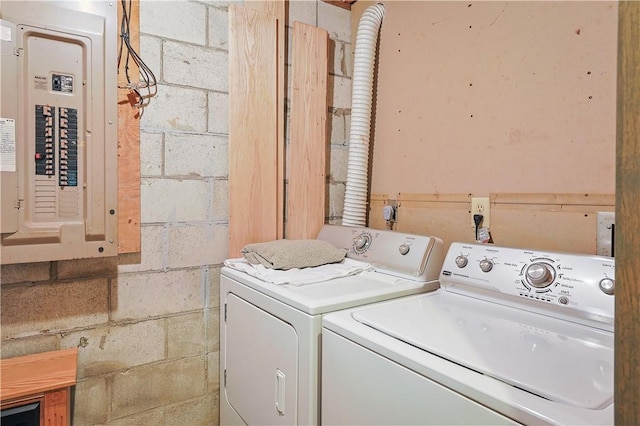 laundry room with concrete block wall, laundry area, electric panel, and washing machine and clothes dryer