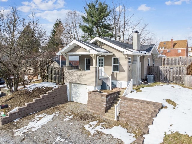 view of front of property featuring a garage, a chimney, fence, and cooling unit