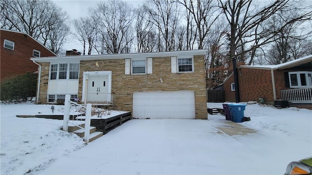 split foyer home with a garage, stone siding, and a chimney