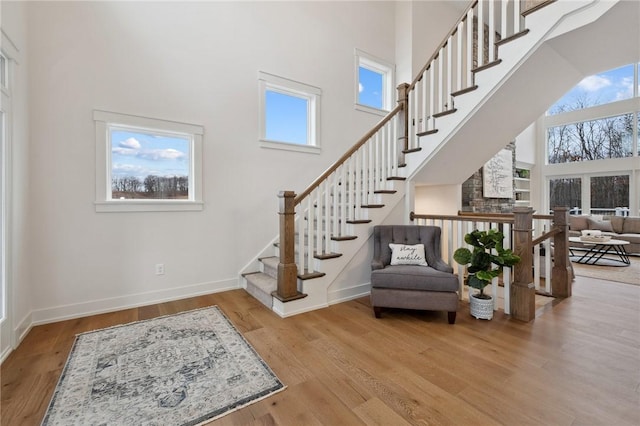 foyer featuring baseboards, wood finished floors, a towering ceiling, and stairway