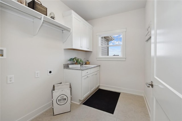washroom featuring baseboards, cabinet space, a sink, and hookup for an electric dryer