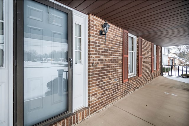 property entrance featuring a porch and brick siding