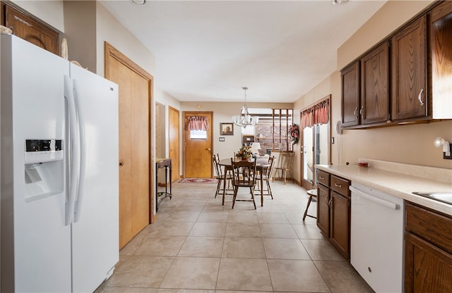 kitchen with pendant lighting, light tile patterned floors, light countertops, an inviting chandelier, and white appliances