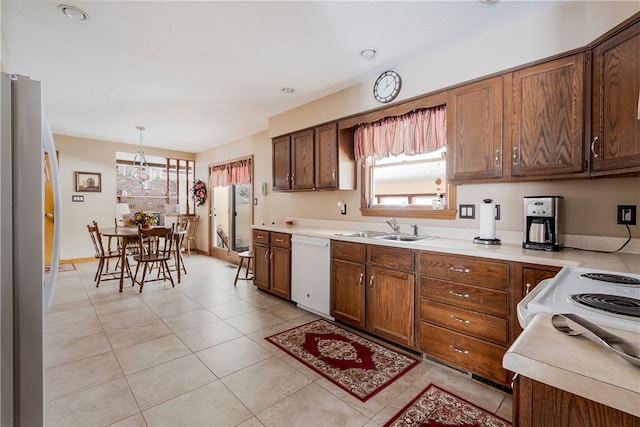 kitchen with freestanding refrigerator, light countertops, white dishwasher, a sink, and pendant lighting