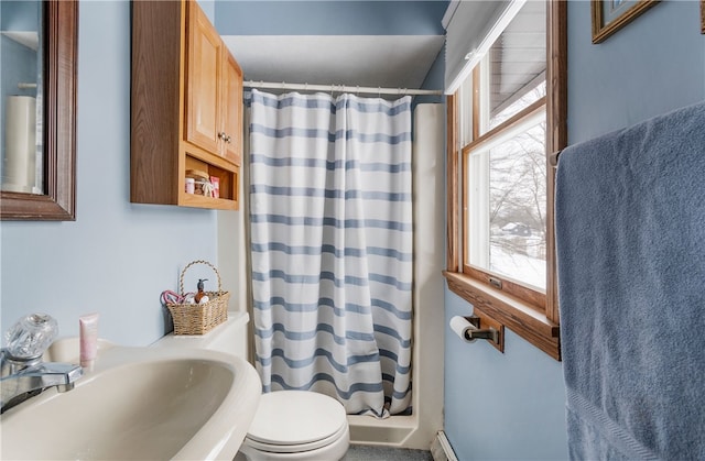 bathroom featuring a shower with shower curtain, a healthy amount of sunlight, toilet, and a sink