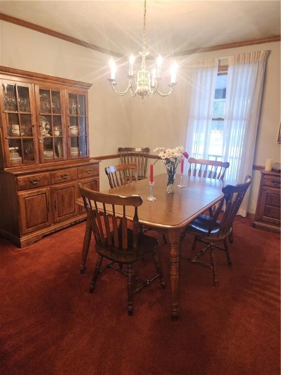 dining space with dark colored carpet, crown molding, and a notable chandelier