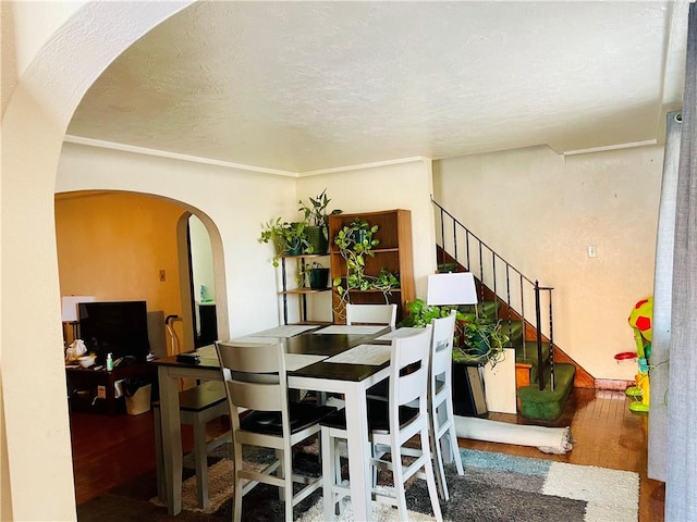 dining room with stairway, arched walkways, and a textured ceiling