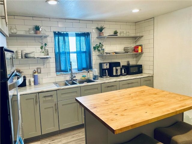 kitchen featuring a sink, a kitchen breakfast bar, wooden counters, decorative backsplash, and open shelves