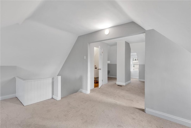 bonus room with lofted ceiling, light carpet, and baseboards